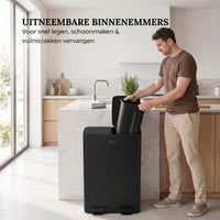 Man tilt uitneembare binnenemmer uit Bayt pedaalprullenbak met 2 vakken van 30 liter in zwart voor eenvoudig legen in een moderne keuken