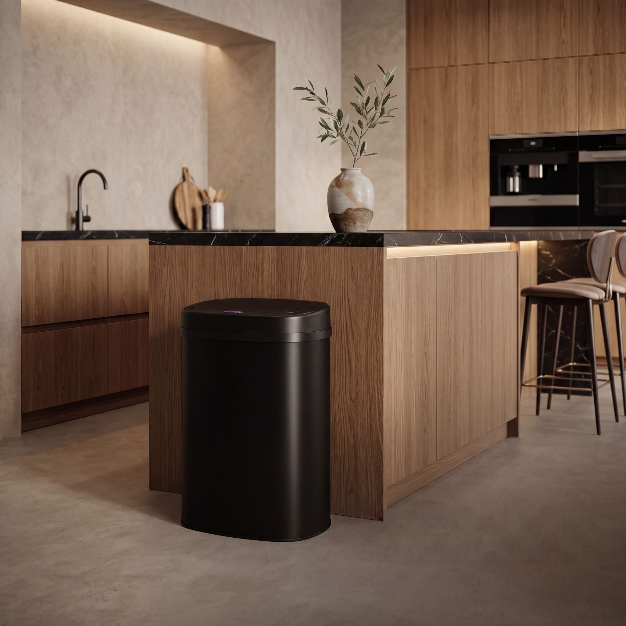 Bayt sensor prullenbak van 60 liter in mat zwart naast een houten keukeneiland in een warm, modern interieur