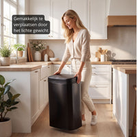 Vrouw verplaatst eenvoudig een Bayt sensor prullenbak dankzij het lichte gewicht in een moderne keuken.